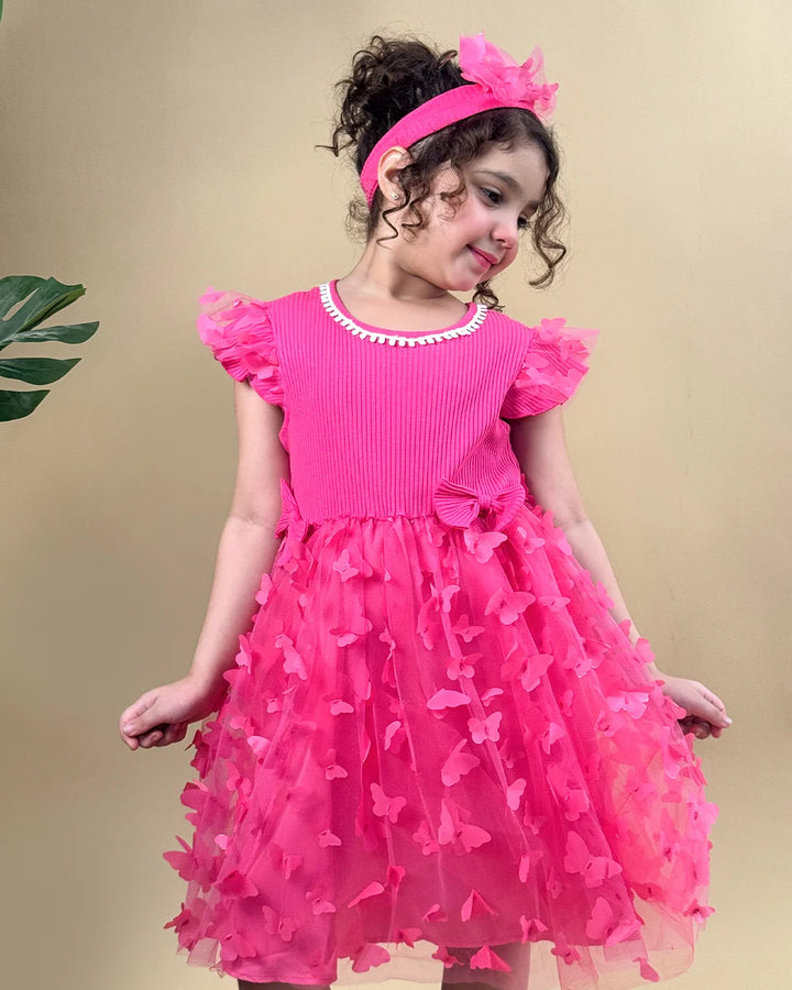 Young girl wearing a pink dress with ruffled sleeves and floral details on a beige background