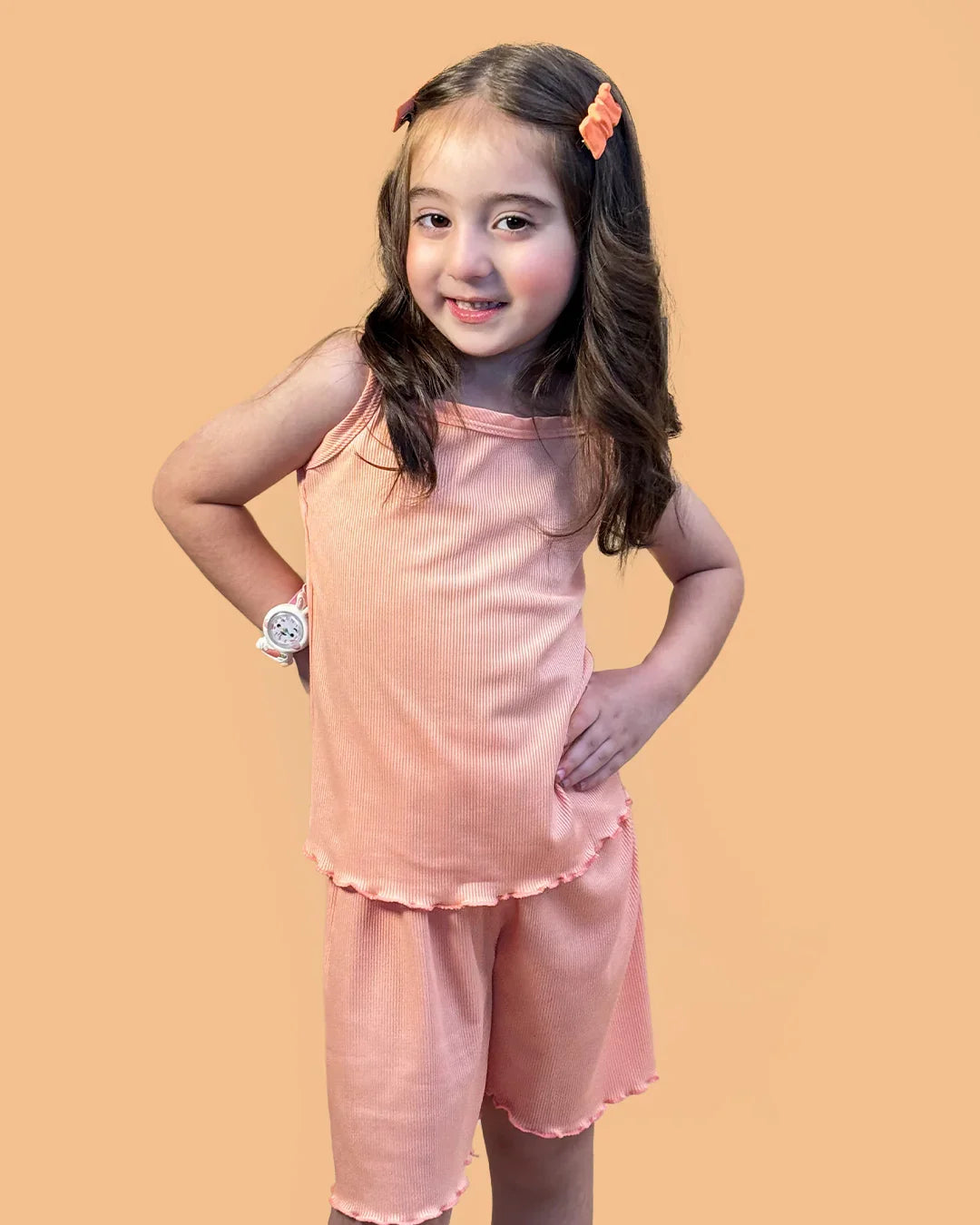 Young girl wearing a pink outfit with a watch on an orange background