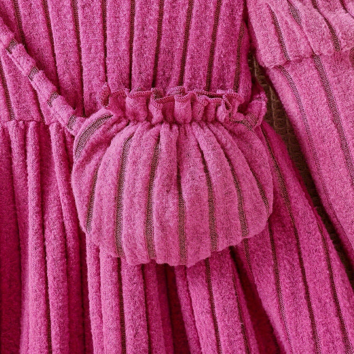 Close-up of a pink textured dress with a ruffled waistband.