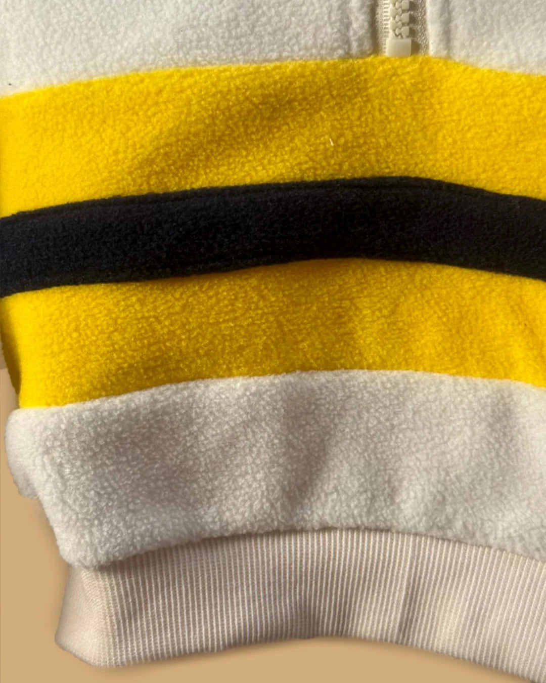 Close-up of a yellow, black, and gray striped fabric on a beige background