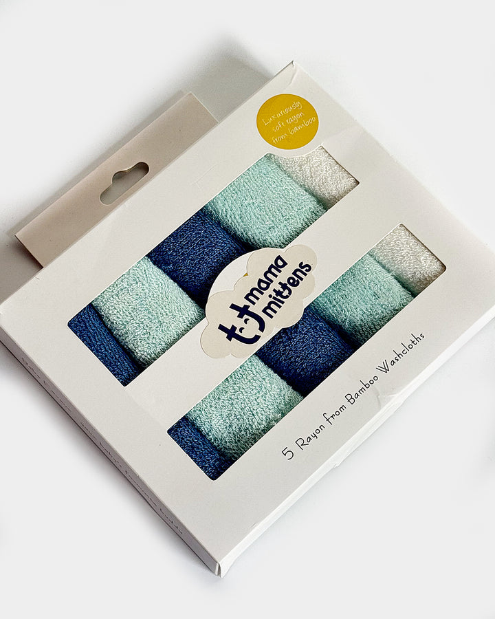 A pack of five solid colored cotton baby washcloths in pastel blue and green, presented in a white packaging with a brand label.