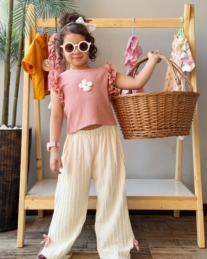 Child holding a wicker basket in front of a wooden rack with clothes