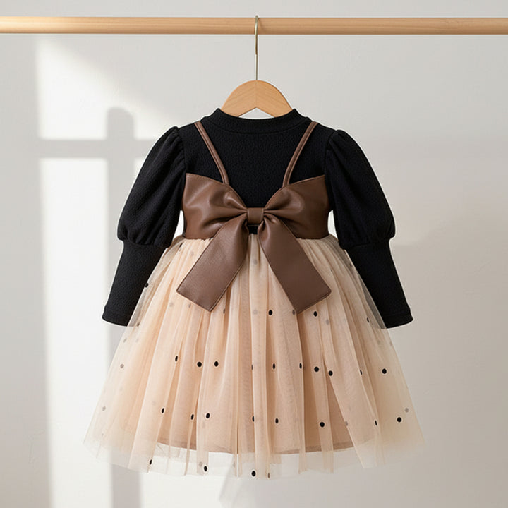 Children's dress with a brown bow back on a hanger against a light background