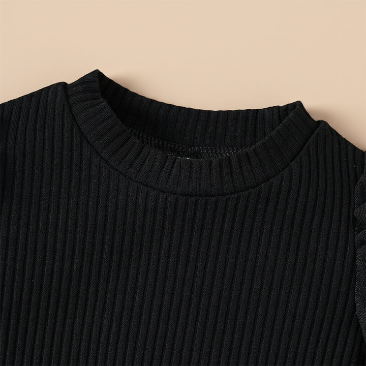 Close-up of a black ribbed sweater collar on a beige background