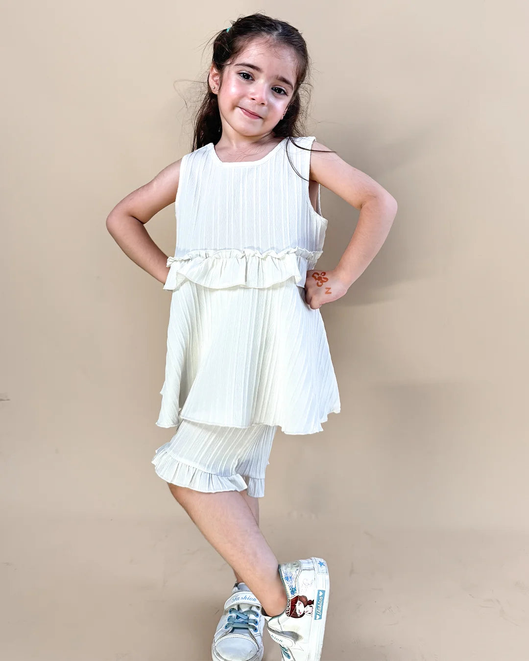 Young girl wearing a white dress with ruffles on a beige background