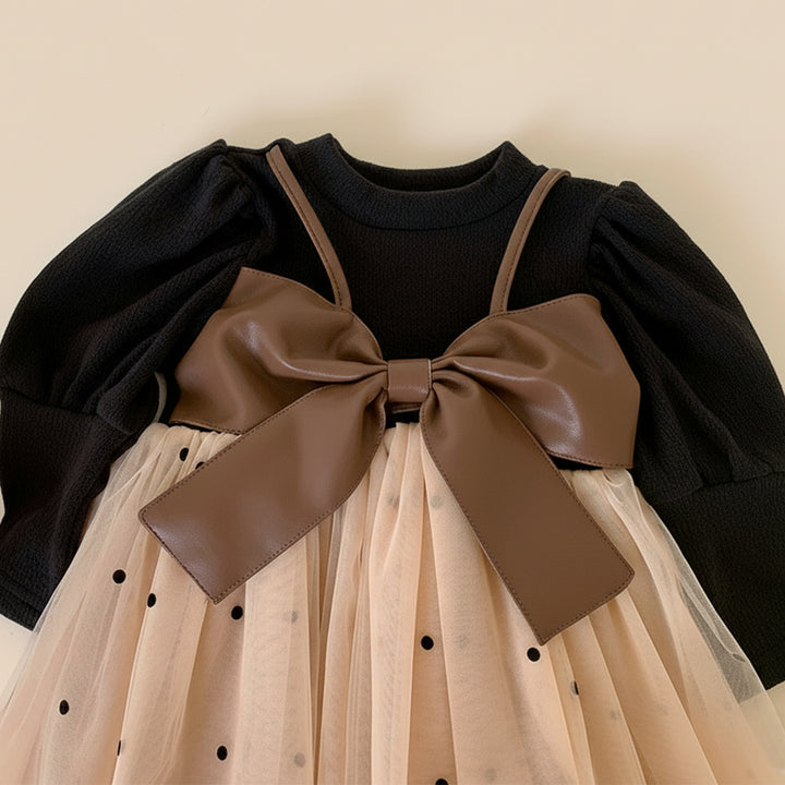 Black top with brown bow and beige skirt with black polka dots on a beige background