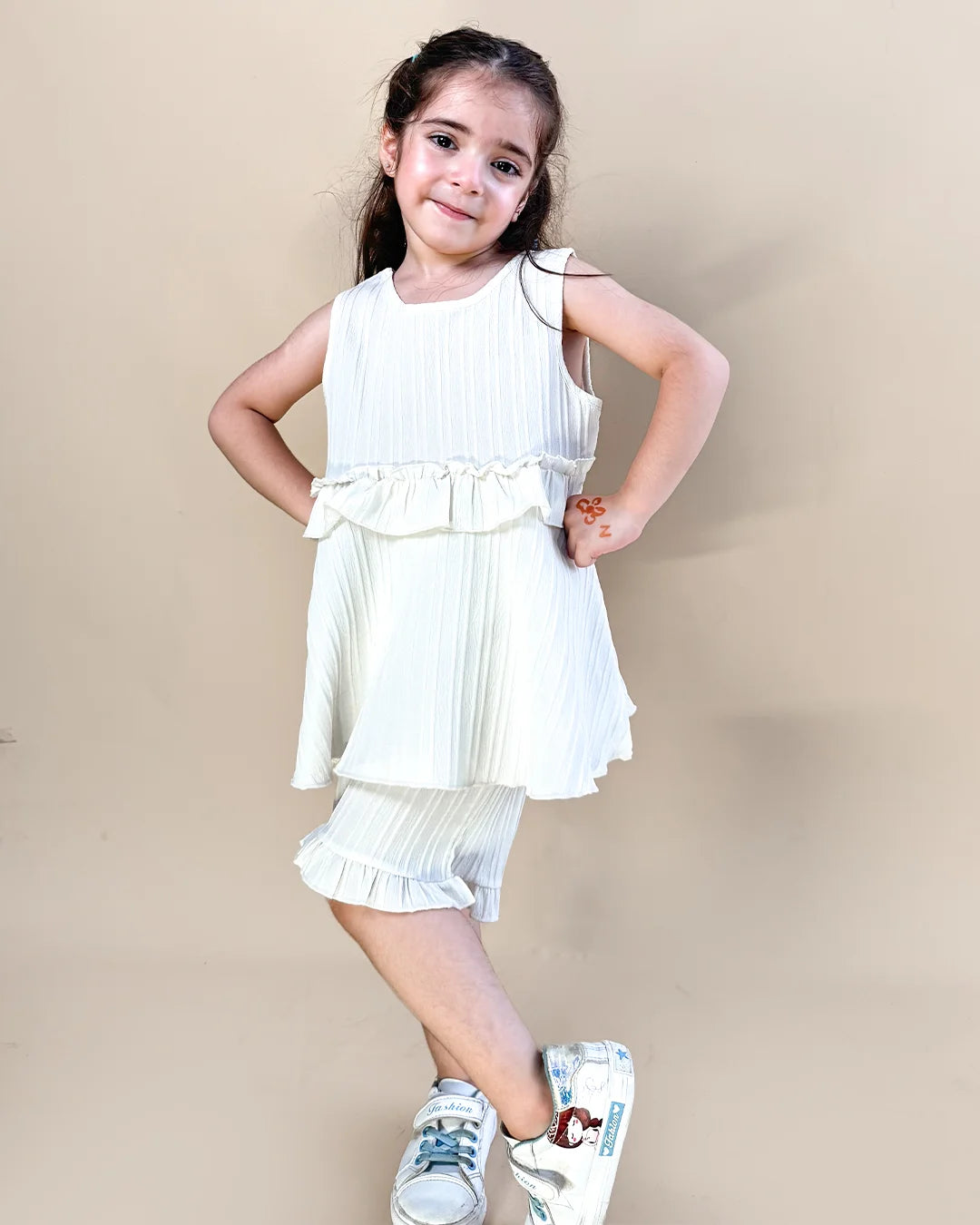 Young girl wearing a white dress with ruffles on a beige background