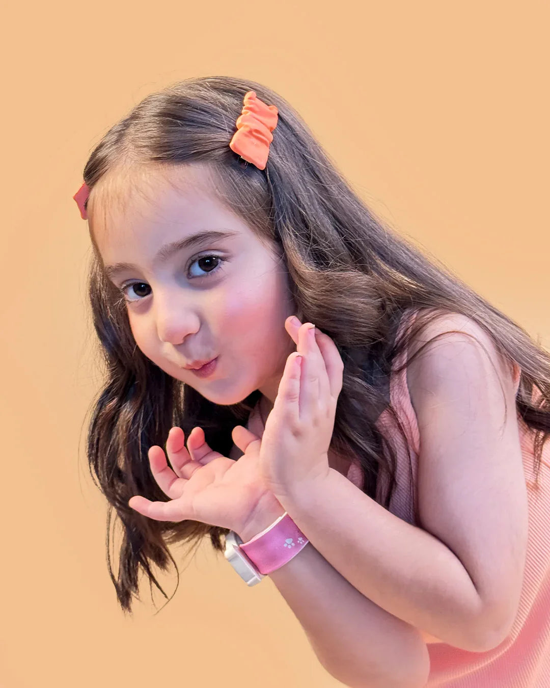 Young girl with a pink hair clip and bracelet on a beige background