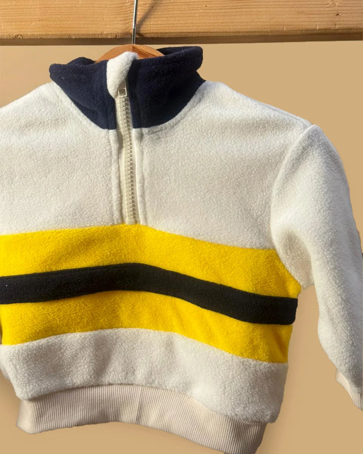 White fleece jacket with yellow and black stripes on a beige background