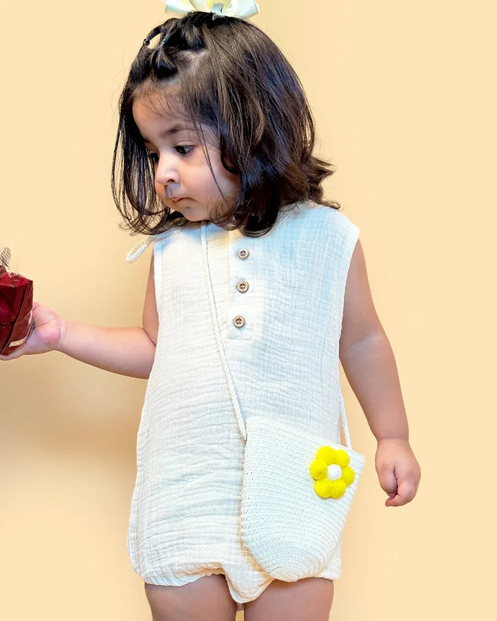 Child wearing a white sleeveless dress with a yellow flower on a beige background
