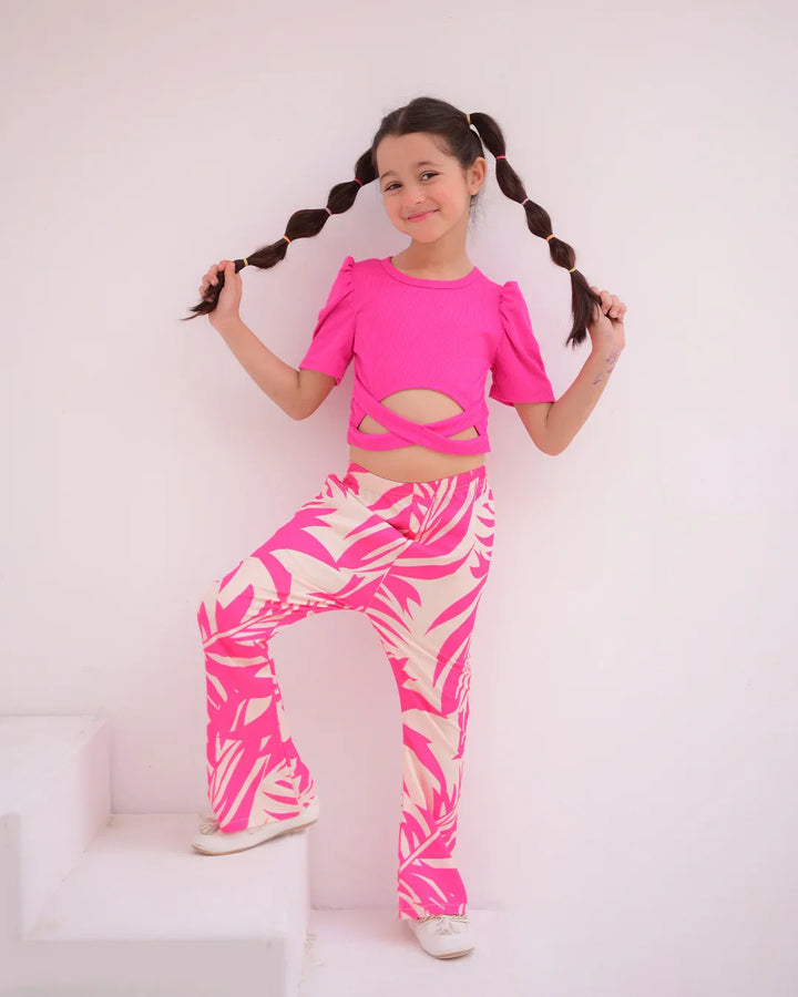 Child wearing a bright pink outfit with cut-out design and zebra print pants on a white background