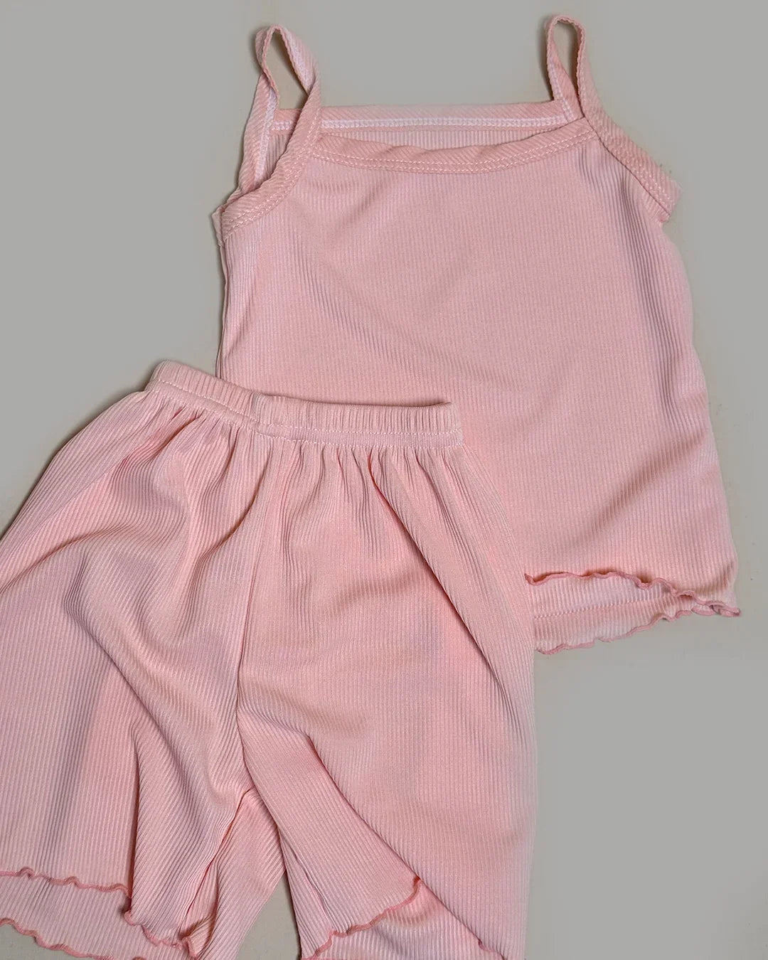 Pink ribbed tank top and pants set on a gray background