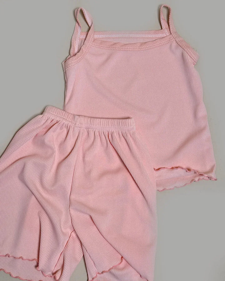 Pink ribbed tank top and pants set on a gray background