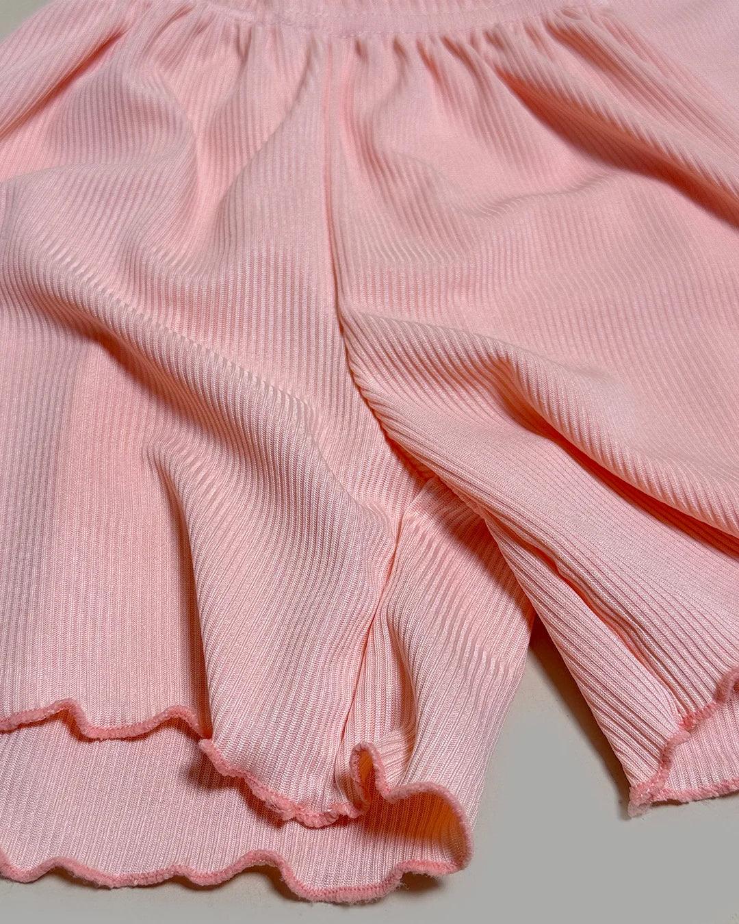 Close-up of pink ribbed fabric with a scalloped edge on a light gray background