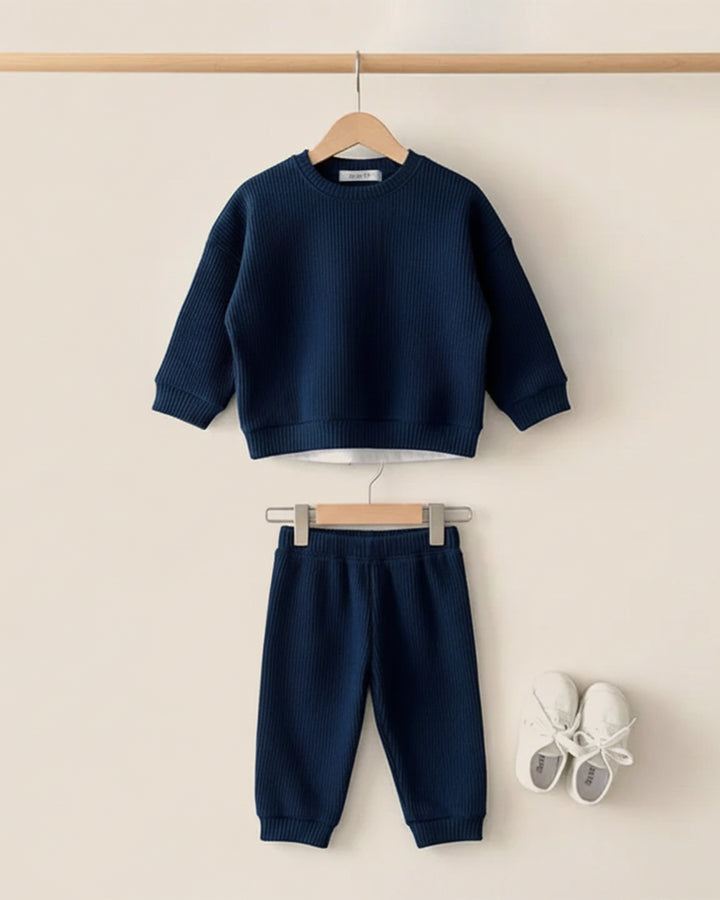 Navy blue sweater and pants set with white shoes on a beige background