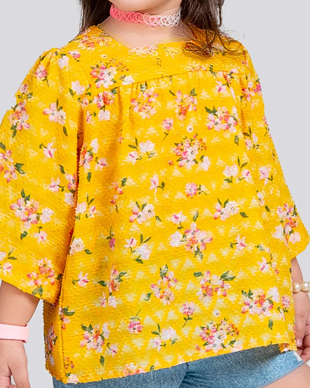 Yellow floral blouse worn by a person on a plain background