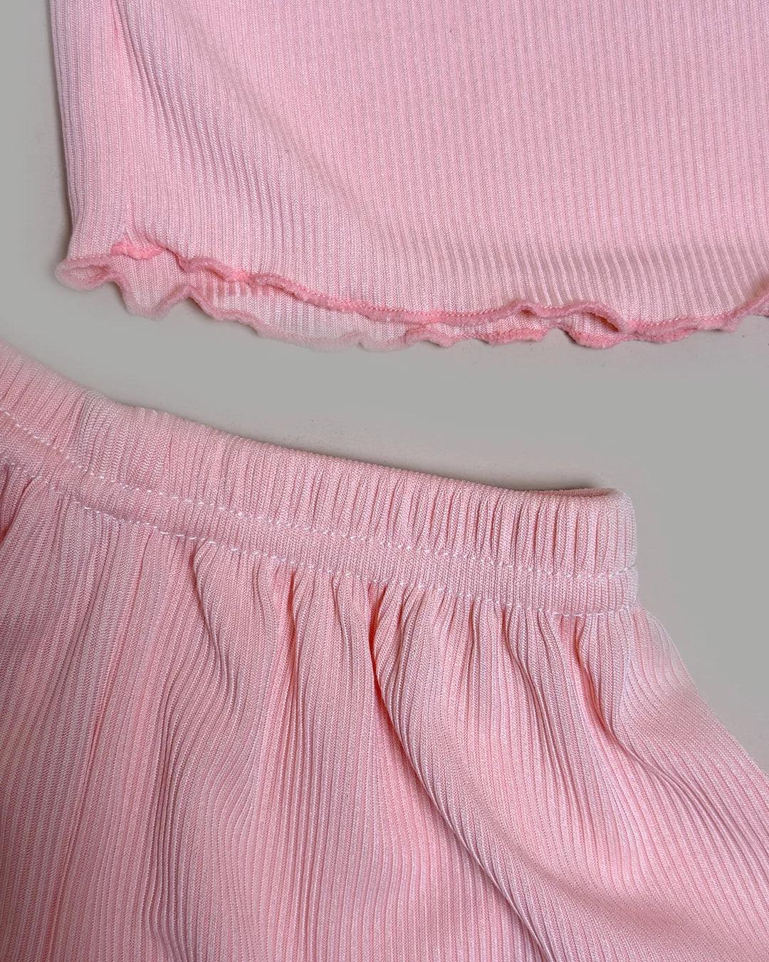 Close-up of a pink ribbed top and skirt set on a gray background