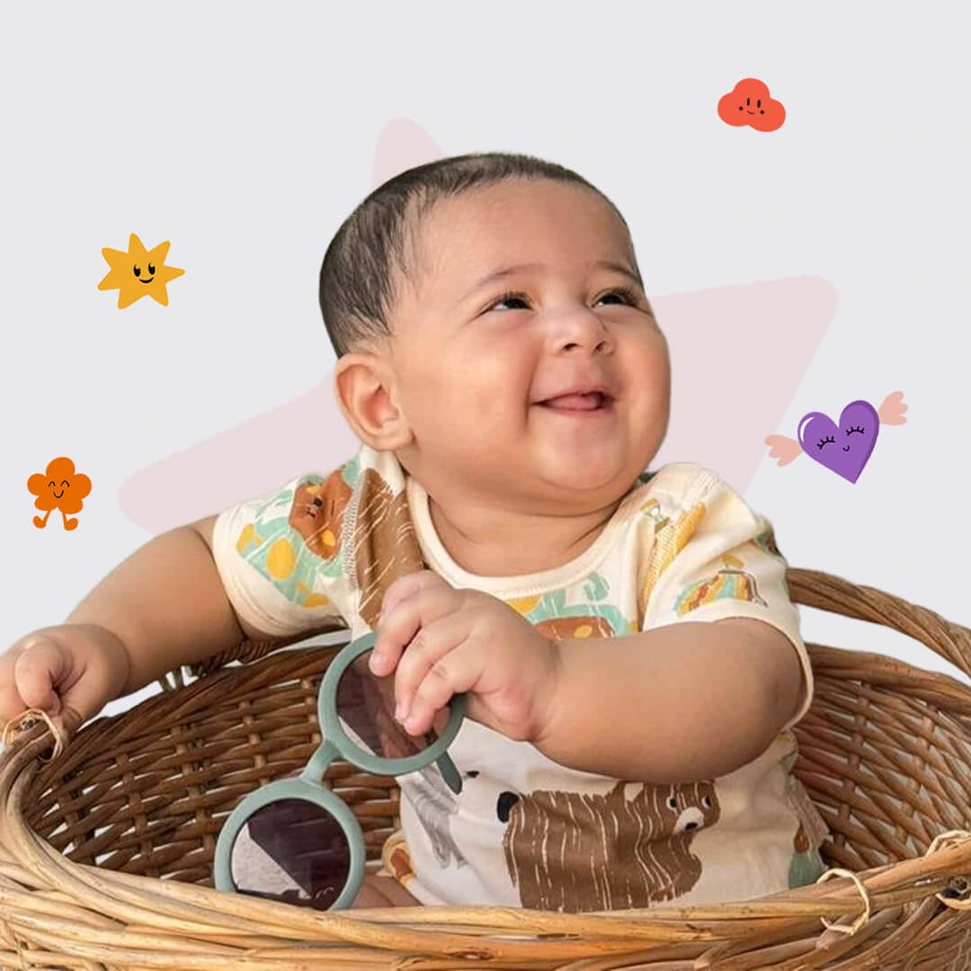Baby sitting in a basket holding sunglasses with colorful stickers around