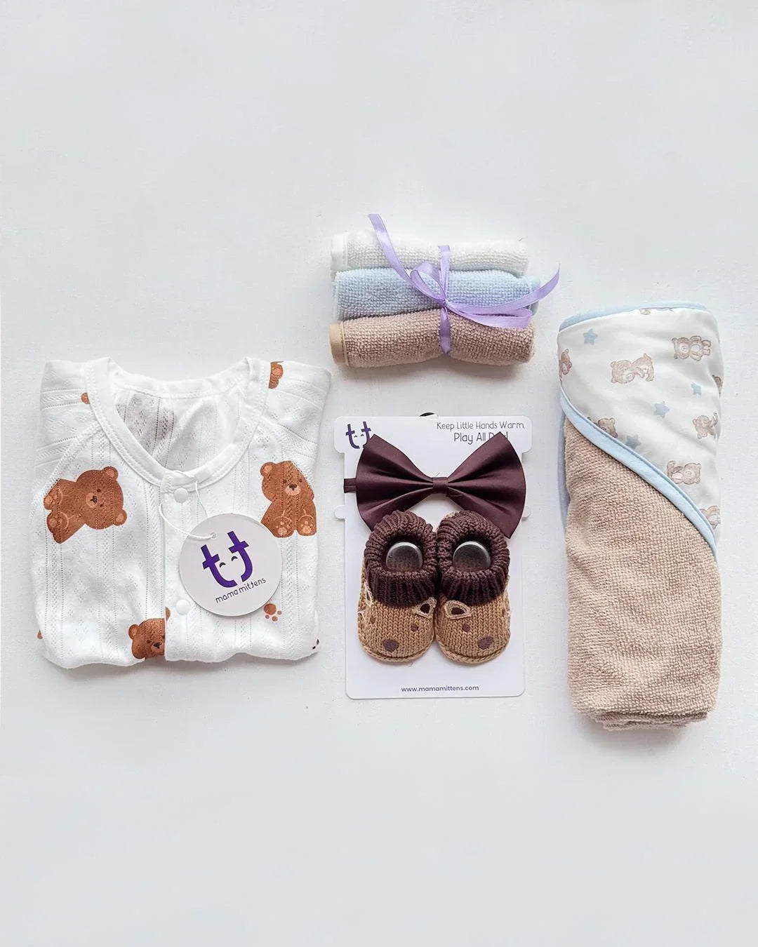 Baby clothing and accessories set including a onesie, bow tie, and socks on a light gray background.