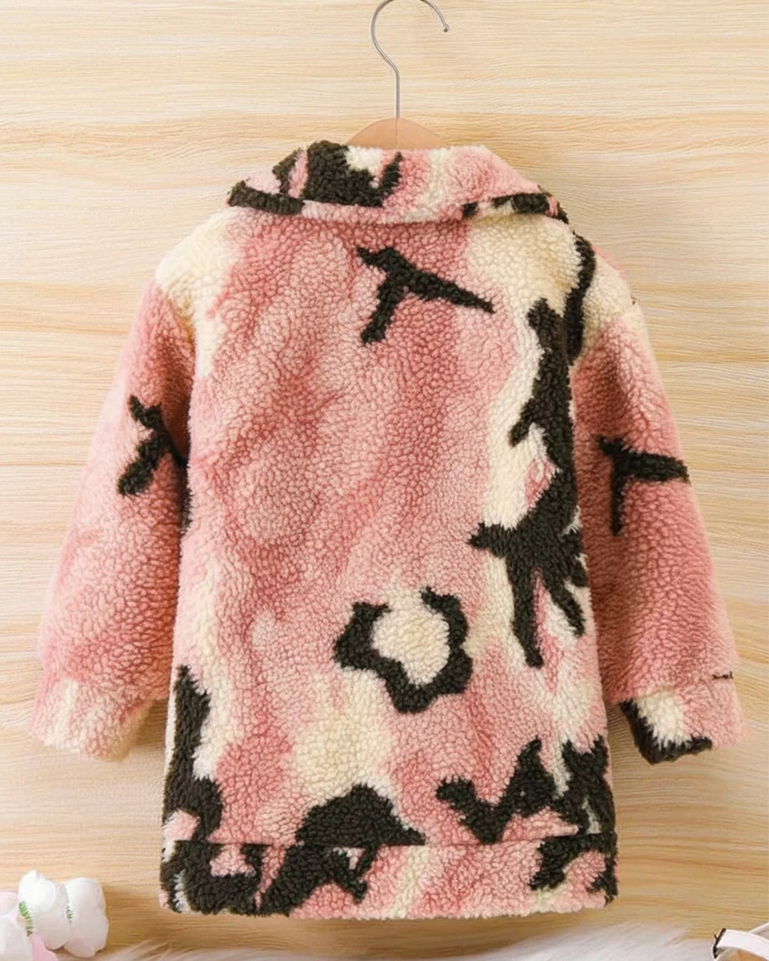 Pink fleece jacket with black patterns on a wooden surface