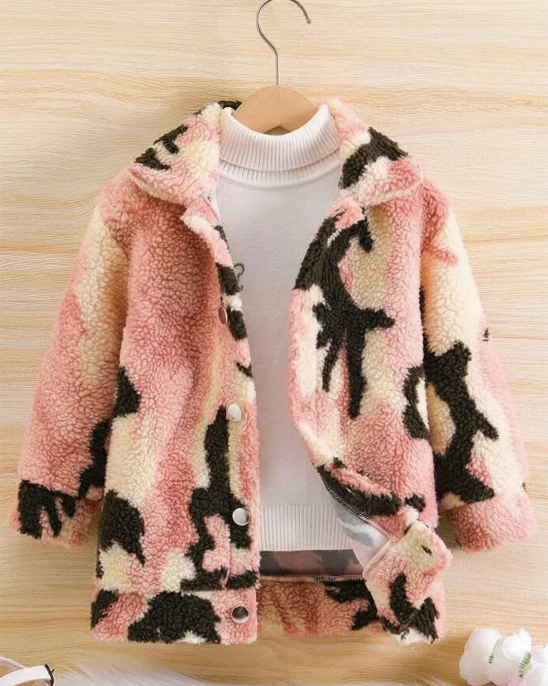 Fluffy pink and black patterned jacket on a wooden surface