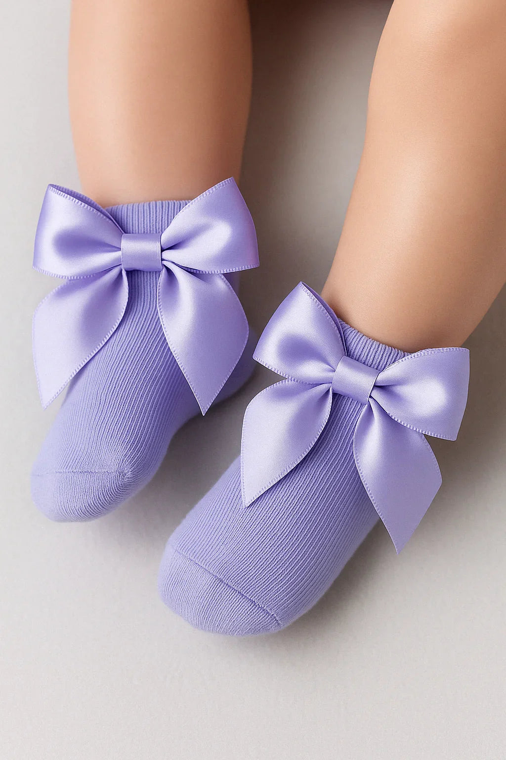 Purple socks with large bows on a neutral background