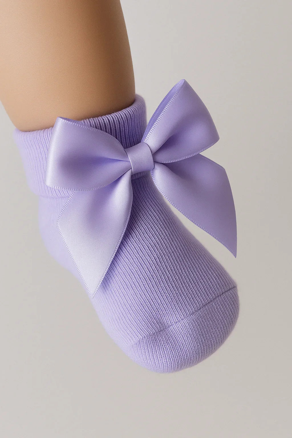 Purple sock with a large bow on a neutral background