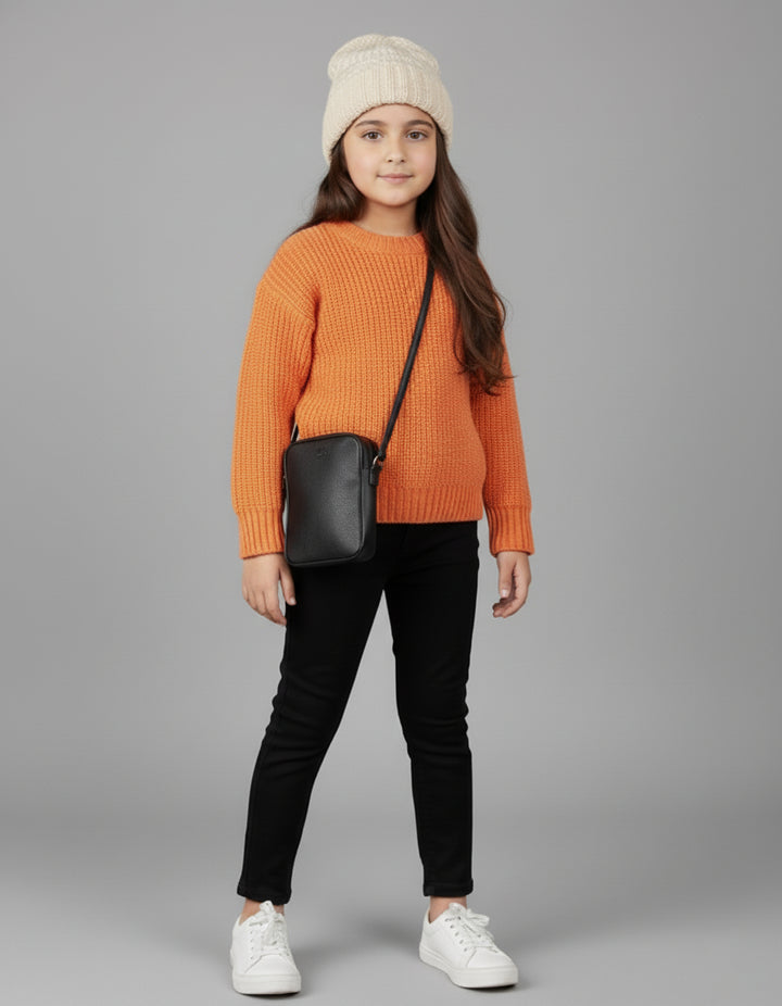 Girl wearing an orange sweater, black pants, white shoes, and a cream beanie with a black crossbody bag on a gray background.