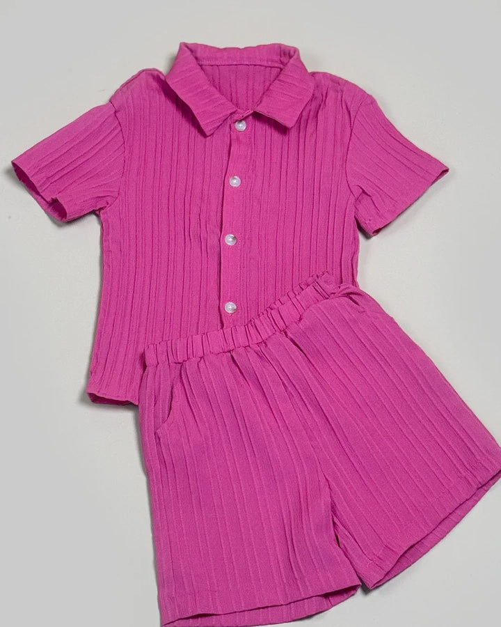 Pink pleated shirt and shorts set on a light gray background