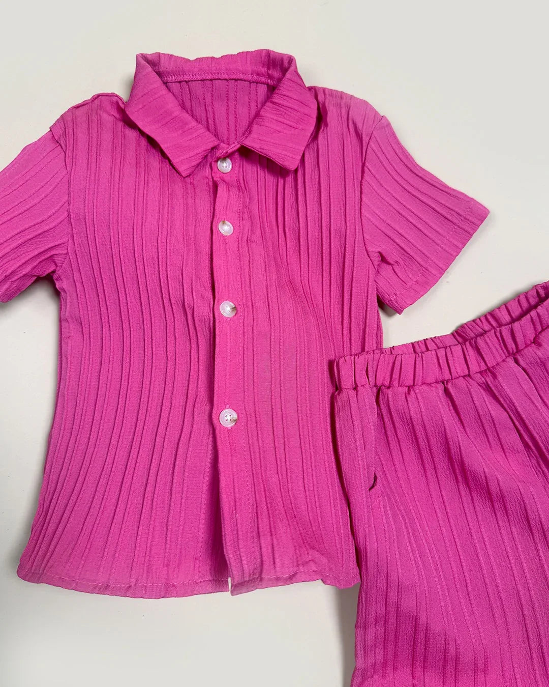 Pink ribbed shirt and pants set on a light gray background