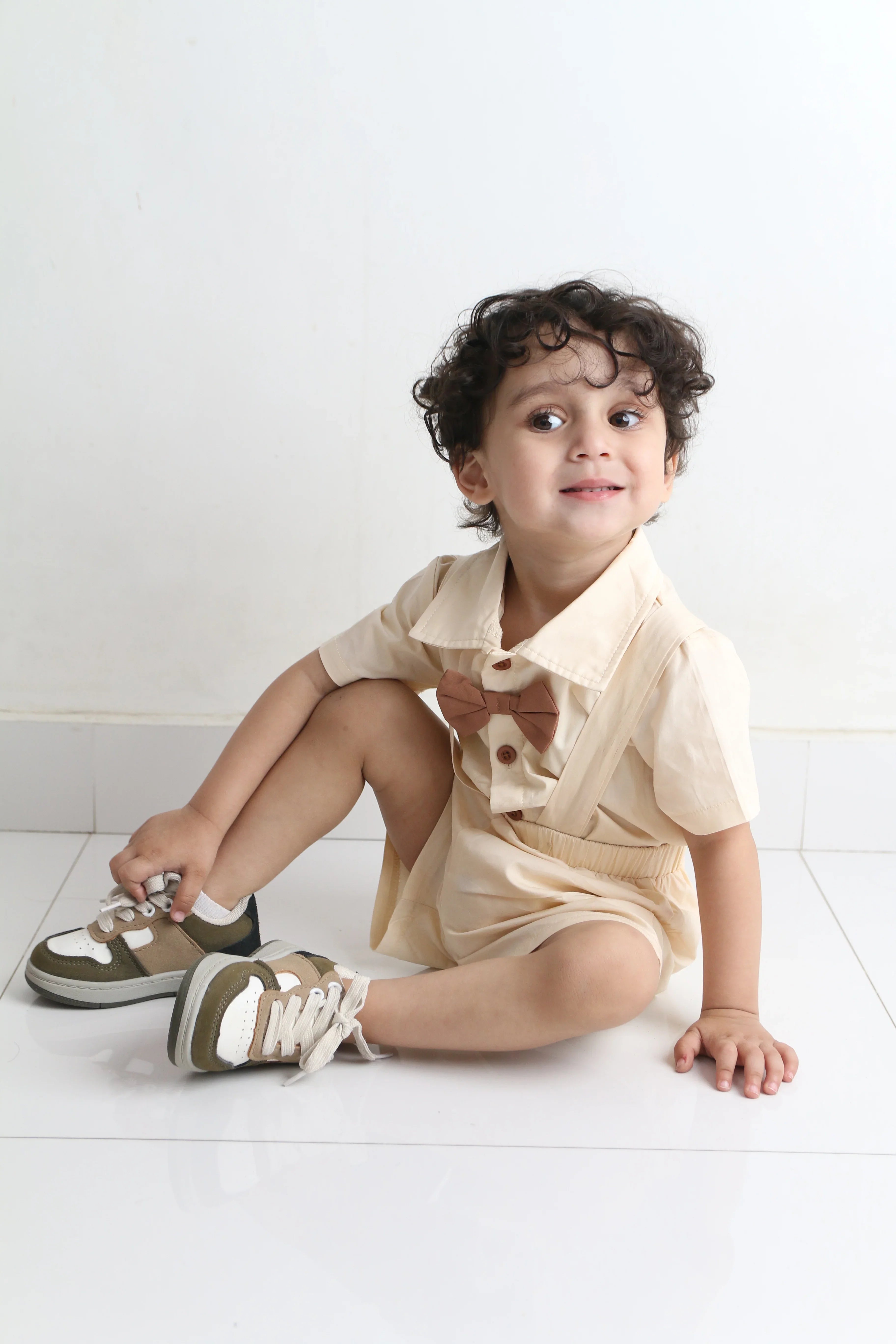 Child wearing beige shoes and a shirt on a white floor