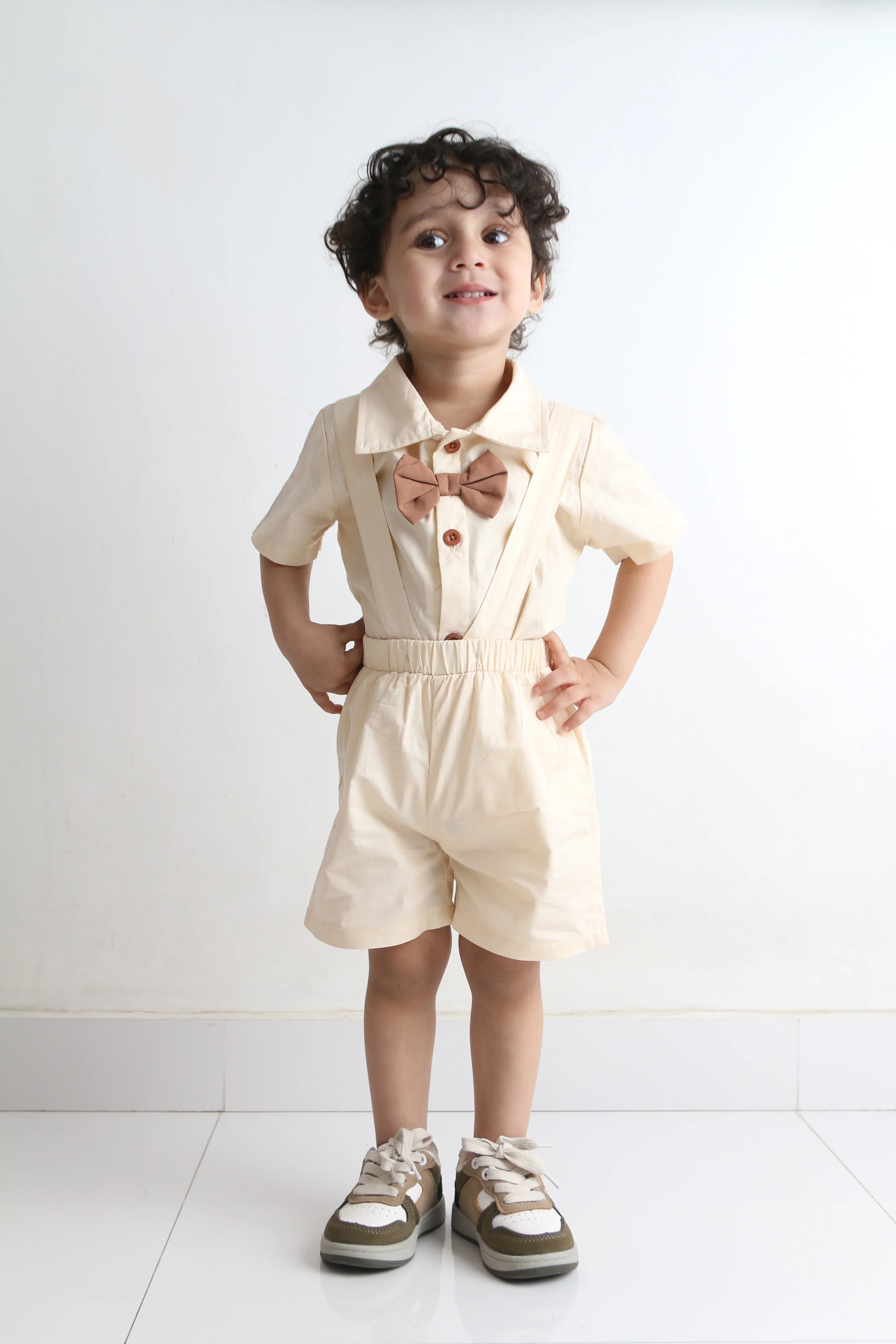 Child wearing a beige dress standing on a white floor