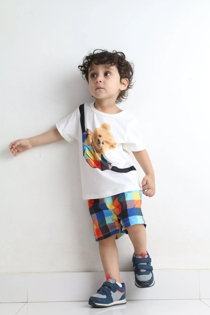 Child wearing a colorful outfit with a white shirt and patterned shorts on a light background