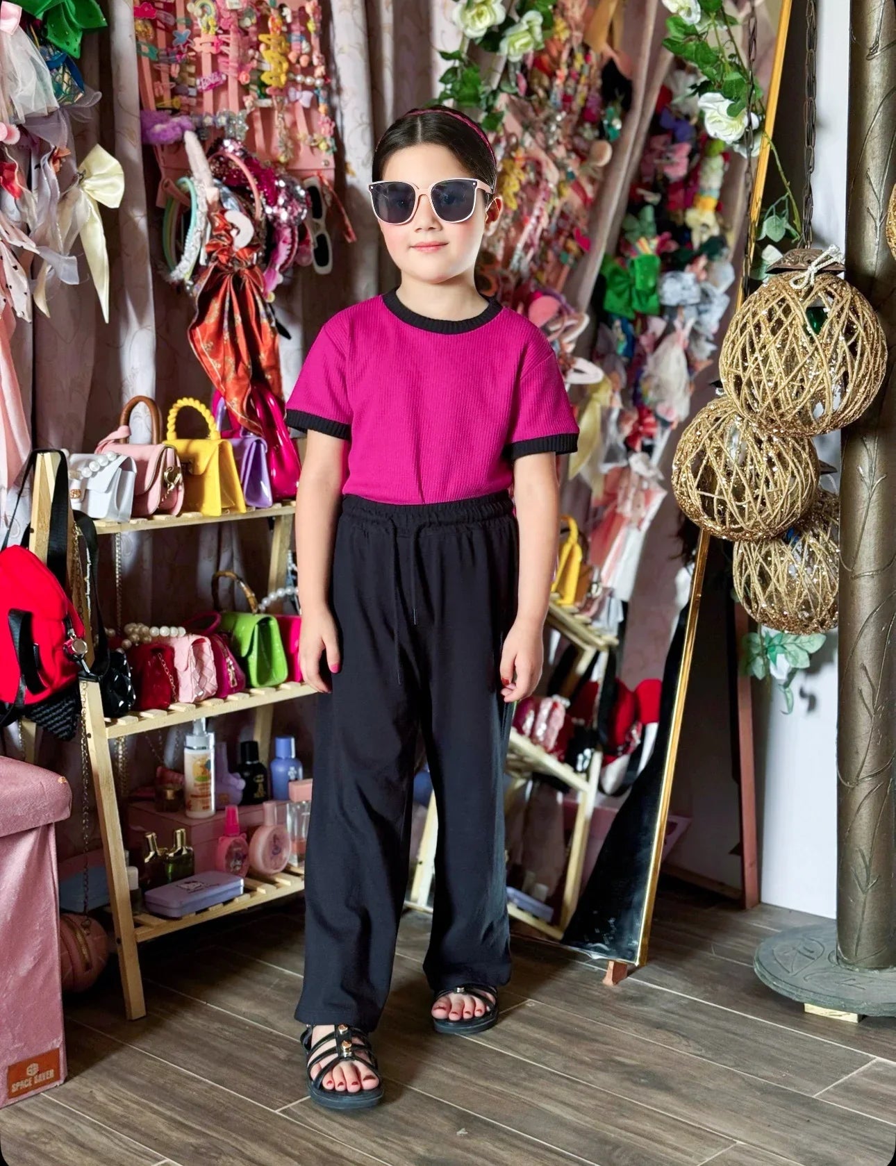 Person wearing a pink shirt and black pants standing in a colorful store.