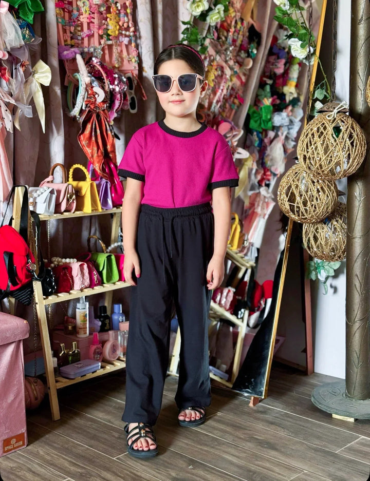Person wearing a pink shirt and black pants standing in a colorful store.