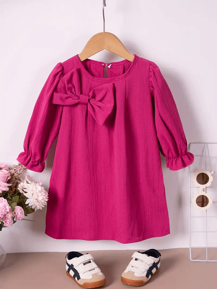 A pink long sleeve princess dress with a bow, displayed on a mannequin with a pair of white sneakers. Seasonal items for spring or fall.