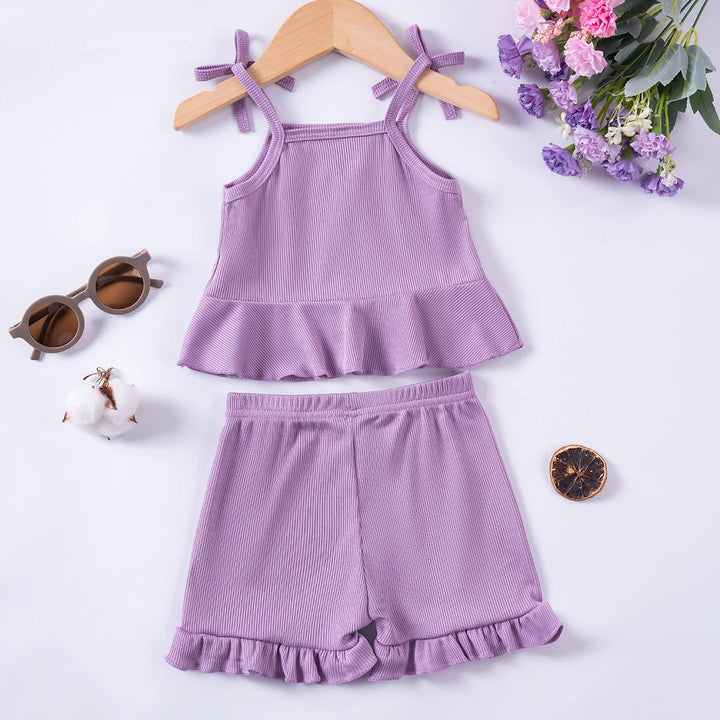 Purple children's tank top and shorts set on a white background with flowers and sunglasses.