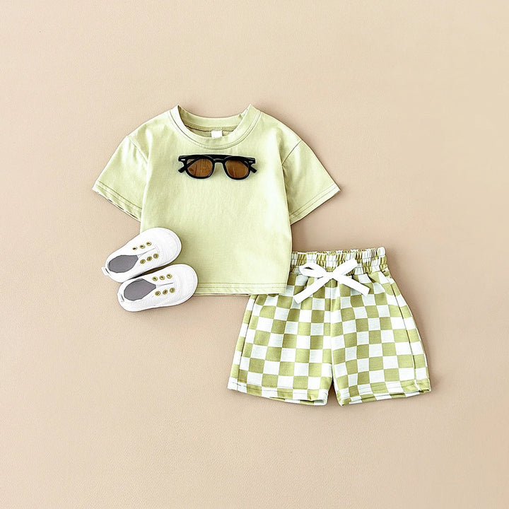 Children's outfit with t-shirt, shorts, and shoes on a beige background