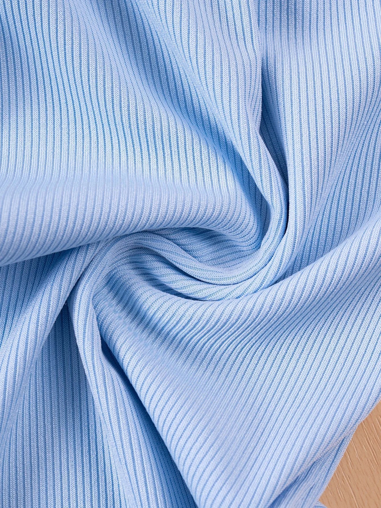 Close-up of blue ribbed fabric with a wooden surface underneath