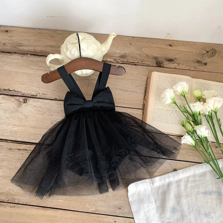 Black tulle dress on a wooden hanger with a teapot and book in the background