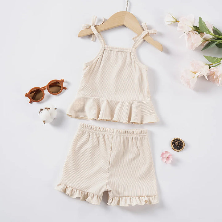 Beige children's top and shorts set on a white background with decorative items.