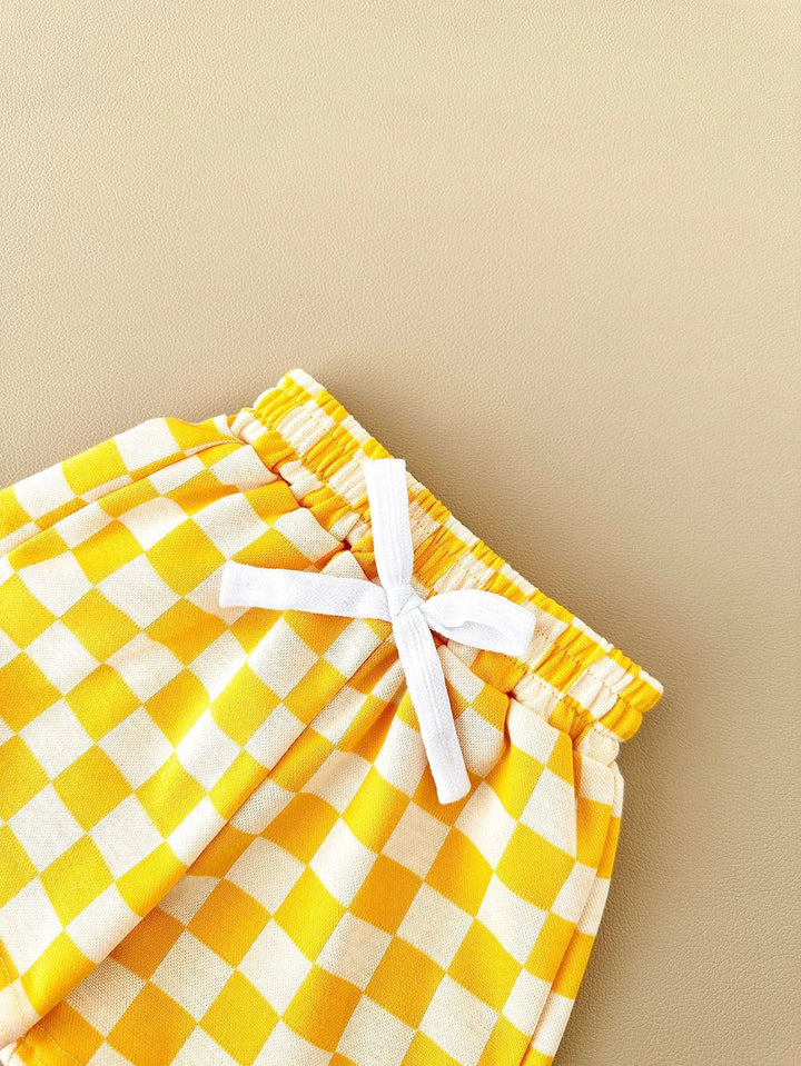 Yellow and white checkered shorts with a drawstring on a beige background