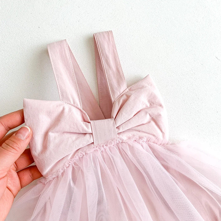 Close-up of a pink dress with a large bow on a white background