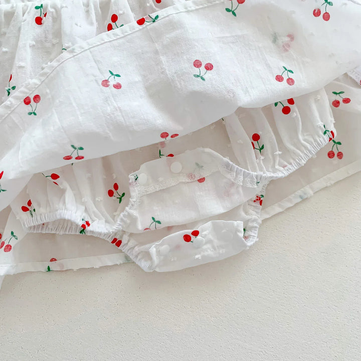 White ruffled fabric with red cherry pattern on a light background