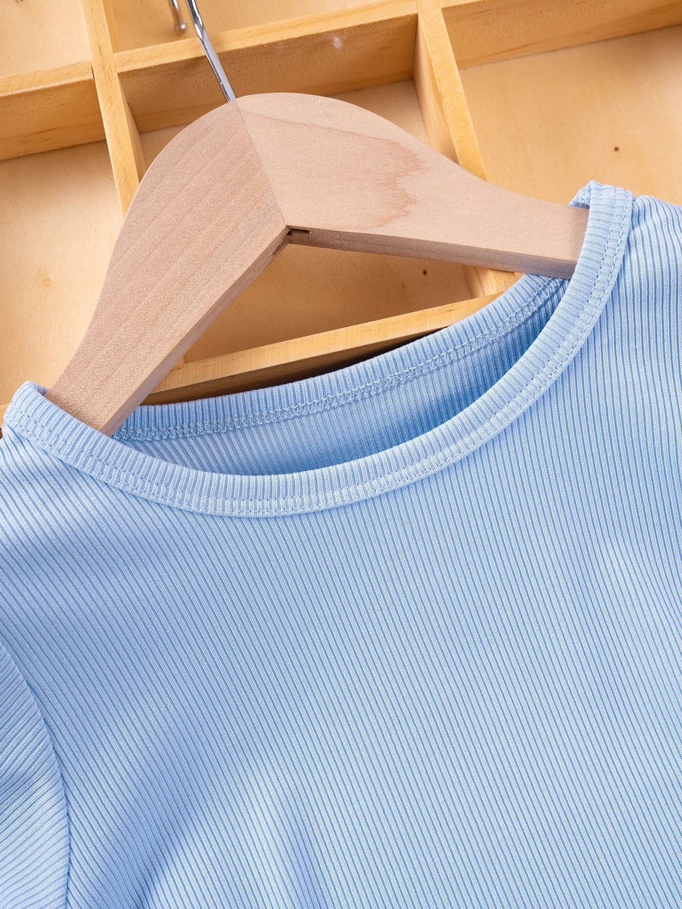 Light blue shirt on a wooden hanger against a wooden background