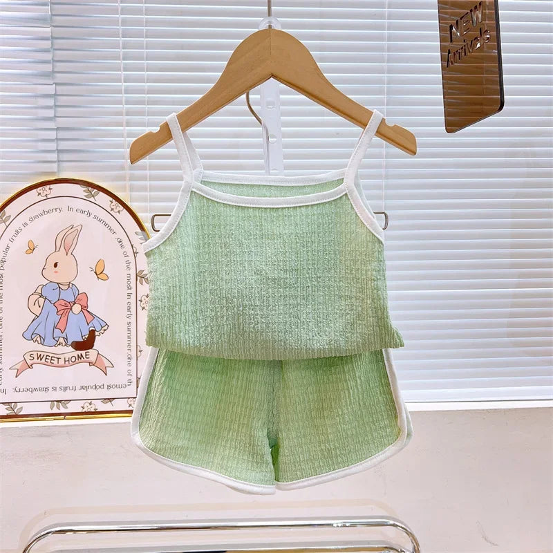 Green children's outfit on a hanger with a decorative plate in the background