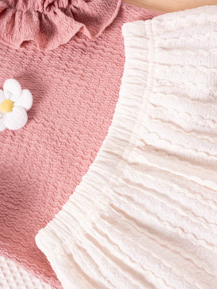 Close-up of pink textured fabric with a white flower and white textured fabric