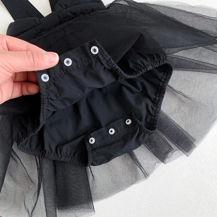 Black petticoat with white buttons held by a hand on a light gray background