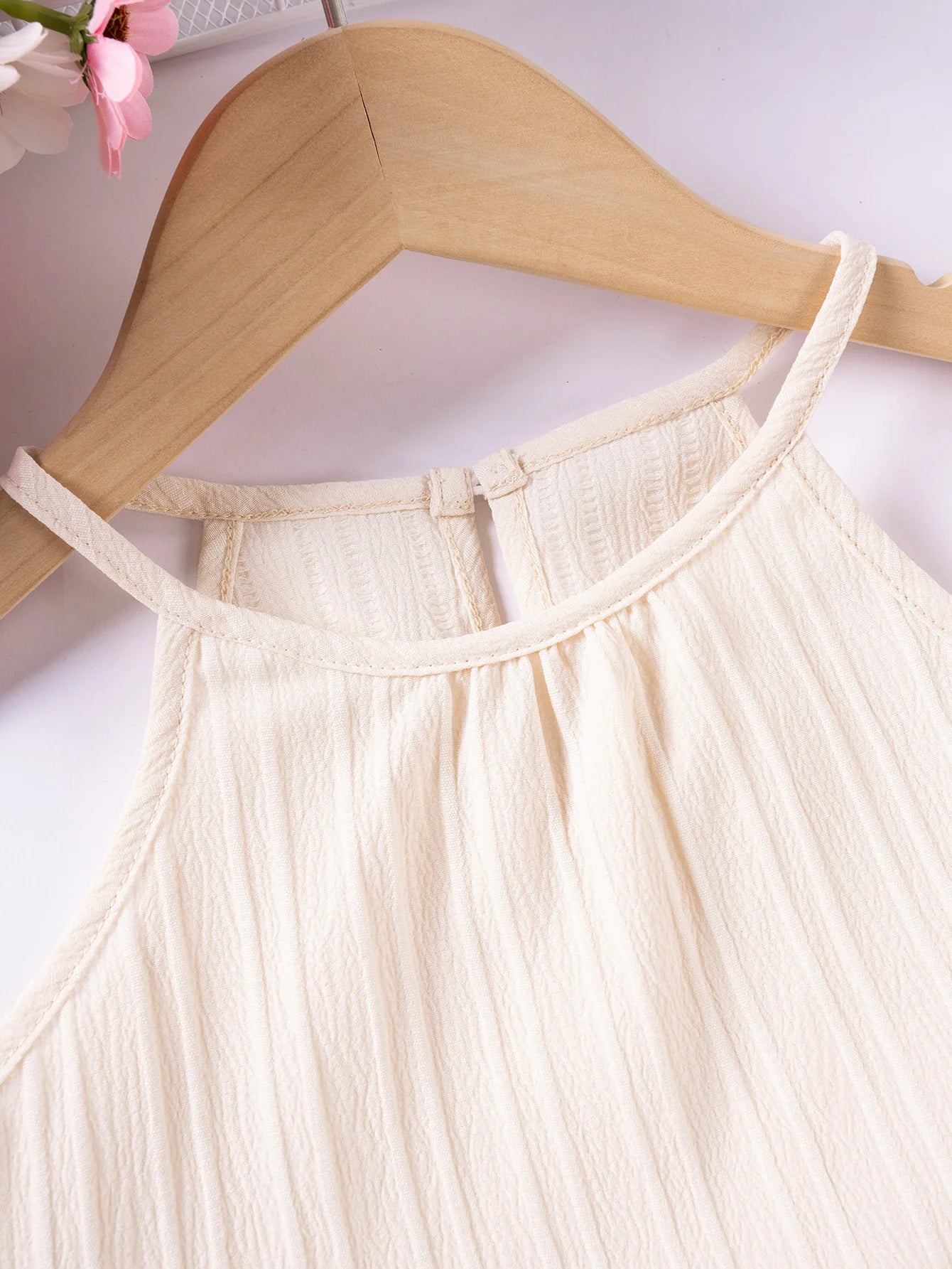 Beige dress on a wooden hanger against a white background
