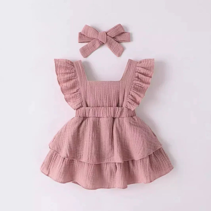 Pink ruffled dress with matching headband on a light gray background